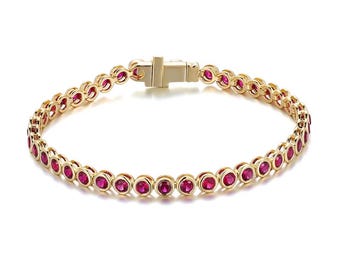 May include: A gold-colored bracelet featuring a series of round, vibrant red gemstones. The bracelet has a secure clasp and a delicate, elegant design. The gemstones are evenly spaced along the bracelet's length.