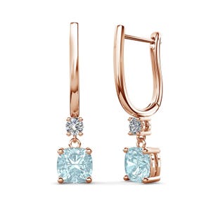 May include: Rose gold earrings with a dangling, light blue, square-cut gemstone. Each earring features a small, round, clear gemstone above the larger square stone. The earrings have a simple, elegant design.