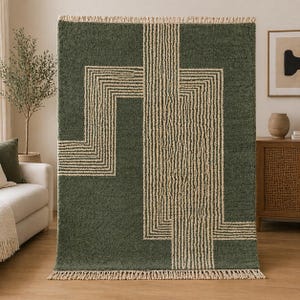 Pu&ograve; includere: Un tappeto verde con un design geometrico. Il tappeto presenta uno sfondo verde scuro con un motivo di linee e forme beige. Ha un bordo con frange ed &egrave; esposto in un soggiorno.