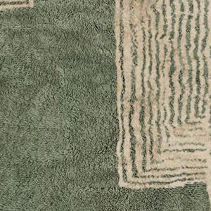 Pu&ograve; includere: Primo piano di un tappeto verde salvia strutturato con un design geometrico. Il tappeto presenta un morbido pelo di peluche e un bordo bianco sporco a contrasto con linee verticali e angoli quadrati. Il design del tappeto aggiunge un tocco moderno a qualsiasi stanza.