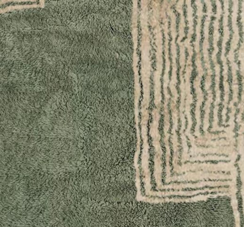 Pu&ograve; includere: Primo piano di un tappeto verde salvia strutturato con un design geometrico. Il tappeto presenta un morbido pelo di peluche e un bordo bianco sporco a contrasto con linee verticali e angoli quadrati. Il design del tappeto aggiunge un tocco moderno a qualsiasi stanza.