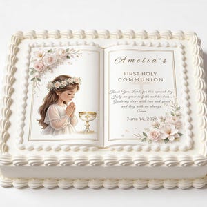 May include: A rectangular cake with white frosting and decorative edges. The cake features an edible image of a girl praying, a chalice, and text that reads "Amelia's First Holy Communion" and the date June 14, 2026. Floral accents are also present.