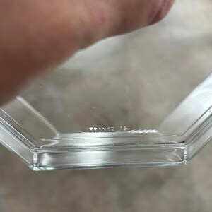 May include: Clear, hexagonal glass dish with the text "FRANCE 15" etched into the glass. The dish has a simple, geometric design and appears to be vintage. The edges are clean and the glass is transparent.