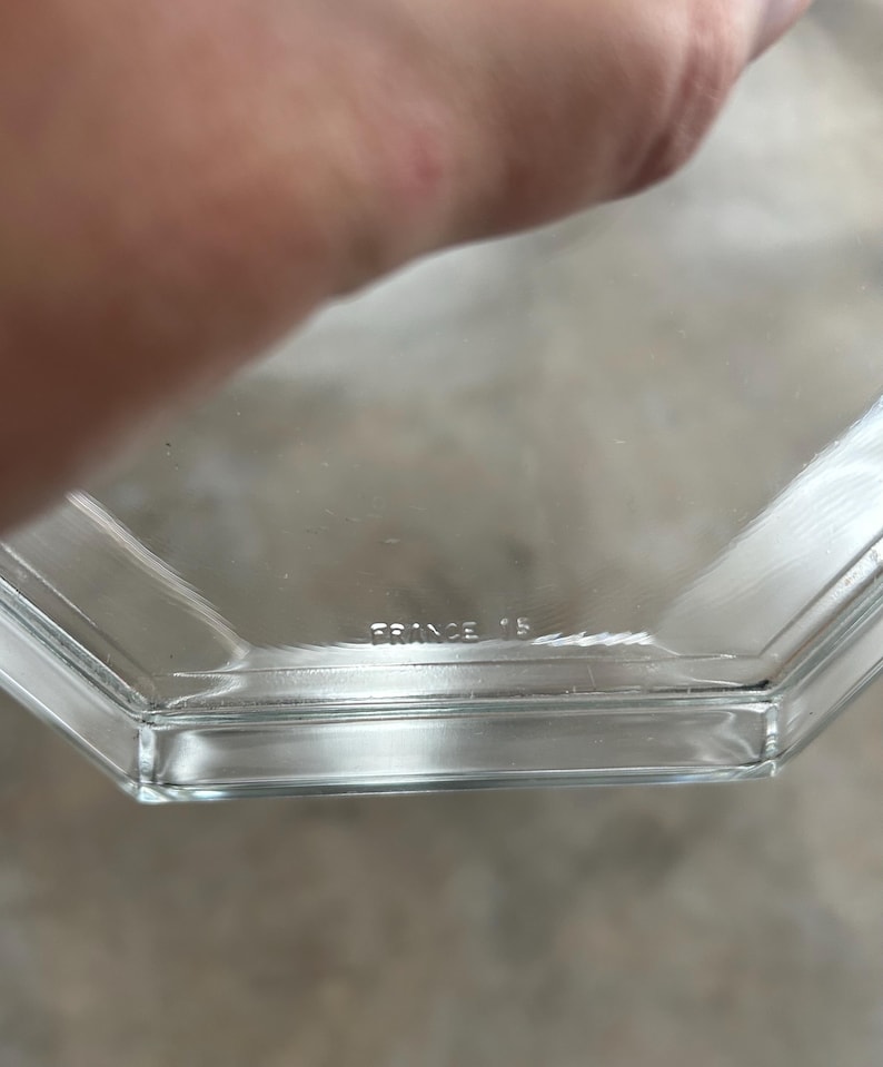 May include: Clear, hexagonal glass dish with the text "FRANCE 15" etched into the glass. The dish has a simple, geometric design and appears to be vintage. The edges are clean and the glass is transparent.