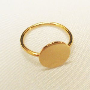 May include: A gold ring with a large, round, flat disc attached to the band.