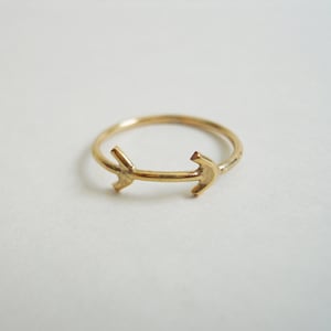 Puede incluir: Un anillo de oro con dos puntas de flecha apuntando en direcciones opuestas.