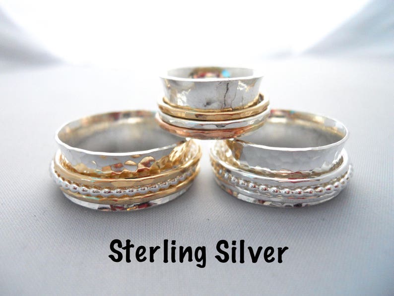 A 10mm wide sterling silver band with thin bands on the top that can spin.