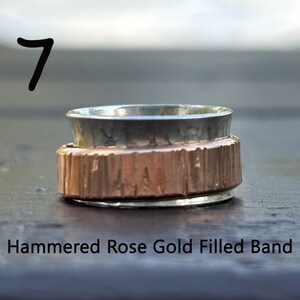 May include: A hammered rose gold filled band ring with a silver outer band. The ring has a textured finish.