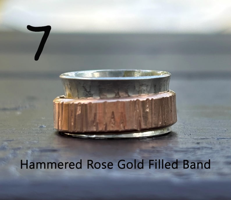 May include: A hammered rose gold filled band ring with a silver outer band. The ring has a textured finish.