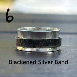 May include: A silver spinning ring with a blackened silver band. The ring is made of two pieces, one silver and one blackened silver.
