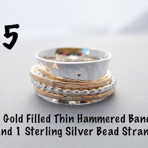 May include: A stack of three rings, two gold filled thin hammered bands and one sterling silver bead strand.