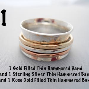 May include: A stack of three thin hammered metal bands. The top band is silver, the middle band is gold, and the bottom band is rose gold.