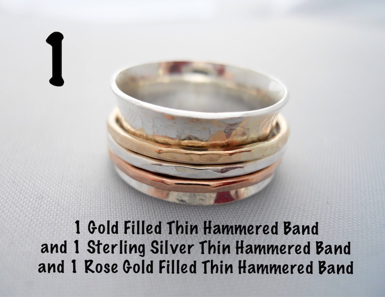 May include: A stack of three thin hammered metal bands. The top band is silver, the middle band is gold, and the bottom band is rose gold.