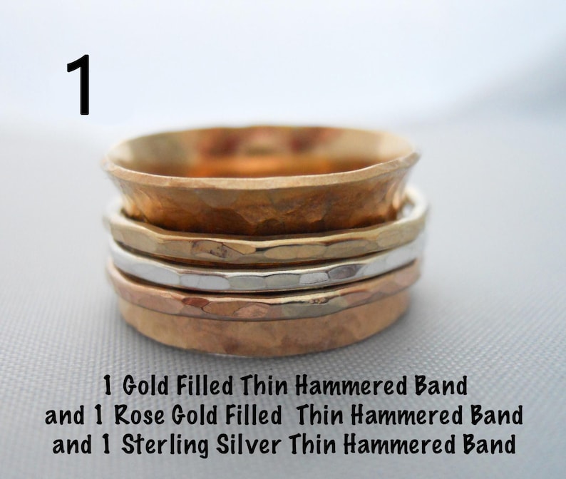 May include: Three thin hammered metal bands stacked on top of each other. The top band is gold filled, the middle band is rose gold filled, and the bottom band is sterling silver.