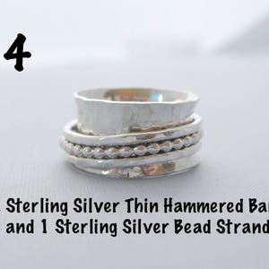 May include: A silver ring with two thin hammered bands and a silver bead strand. The ring is on a white surface. The number 4 is written above the ring.