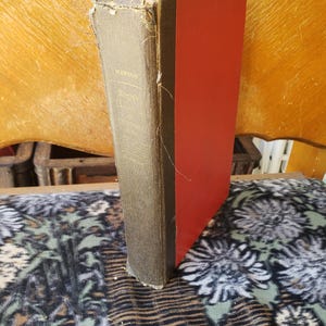 May include: A hardback book with a dark grey fabric spine and bright red covers. The spine features gold lettering that reads Mawson and Roget. The fabric on the spine shows signs of wear and fraying along the edges and top corner.