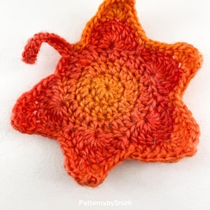Large crochet maple leaf coaster made with ombré autumn yarn. Handmade fall home décor perfect for table settings, seasonal decorations, or as a unique crochet gift