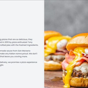 May include: A close-up of a gourmet burger with a golden bun, melted cheese, ham, and a yellow sauce. A knife is inserted through the top bun. The burger is on a wooden surface.