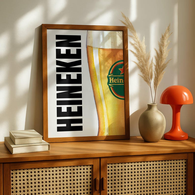Puede incluir: Impresi&oacute;n enmarcada con el logotipo de Heineken y un vaso de cerveza parcialmente visible. La palabra "HEINEKEN" est&aacute; impresa verticalmente en negro. La impresi&oacute;n se muestra en un mueble de madera con elementos decorativos.