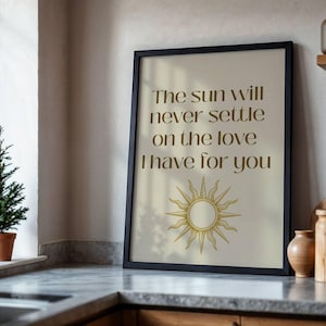Puede incluir: Una lámina enmarcada con fondo beige y el texto en marrón oscuro "The sun will never settle on the love I have for you" sobre una ilustración lineal dorada de un sol con rayos que irradian hacia el exterior.