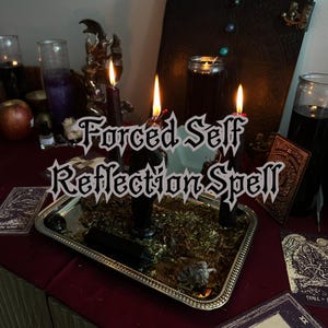 May include: A still life arrangement featuring three lit black candles on a silver tray with dried herbs. The text "Forced Self Reflection Spell" is overlaid on the image. Other items include tarot cards and glass jars.