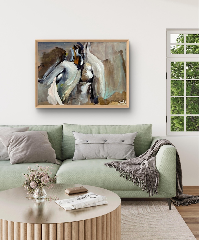 May include: Abstract painting in a wooden frame. The artwork features a blend of white, brown, and teal brushstrokes. The painting hangs above a green sofa with gray pillows and a round coffee table.