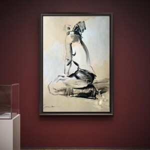 May include: A framed black and white artwork depicting a seated figure in a minimalist style. The artwork is displayed on a dark red wall, with a wooden floor visible below. The figure is rendered with bold brushstrokes, creating a sense of movement and emotion.