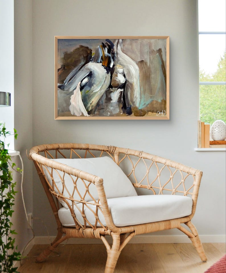 May include: Abstract painting in a wooden frame, featuring brushstrokes of white, gray, and brown. The artwork hangs above a wicker armchair with a white cushion and pillow. The room has a neutral color palette.