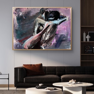 May include: Abstract artwork in a gold frame, depicting figures in black, grey, pink, and purple hues. The painting hangs above a black sofa with a brown cushion, a white coffee table, and a dark rug in a living room setting.