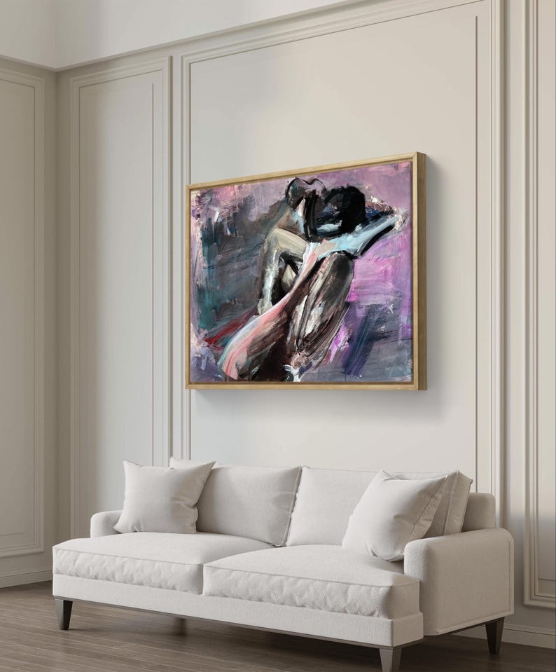 May include: Abstract artwork depicting a seated figure in purple, black, and pink hues. The painting, in a gold-toned frame, hangs above a white sofa with cushions. The artwork's style is modern and expressive, suitable for contemporary interiors. The painting is in a gold-toned frame.