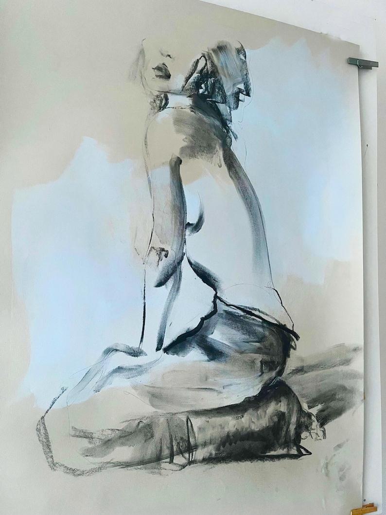 May include: A charcoal drawing of a seated figure, rendered in shades of gray and black on a light beige background. The artwork depicts a person in a seated pose, with a focus on the form and shadows, creating a sense of depth and texture.