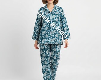 May include: A teal pajama set with a white floral pattern and white trim. The long-sleeved top has a collared neckline and button-down front. The matching pants are straight-legged. The text "Made in India" is visible on the top.