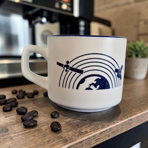 Puede incluir: Un juego de tres tazas de cerámica con un acabado moteado y mate. Las tazas son de color crema, gris claro y gris oscuro. Cada taza tiene un diseño simple y minimalista y un asa redondeada.