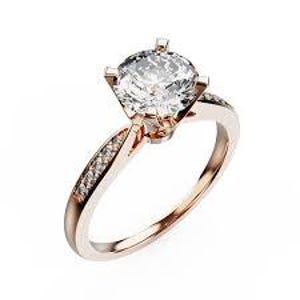 May include: Rose gold engagement ring featuring a large, clear, round-cut diamond held by four prongs. The band is adorned with smaller diamonds, adding sparkle. The ring is set against a white background.