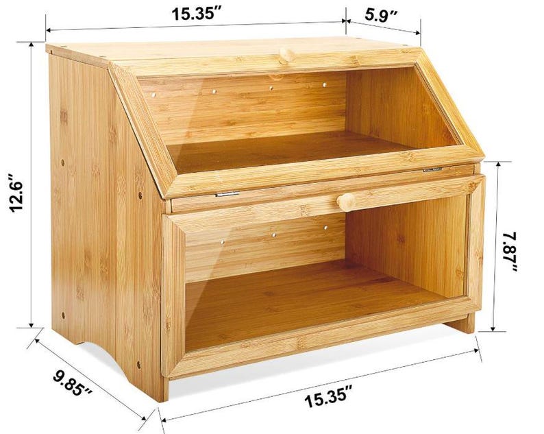 May include: A bamboo bread box with a clear glass door and a hinged top. The box is 15.35 inches wide, 12.6 inches tall, and 5.9 inches deep. The bottom compartment is 7.87 inches tall. The bread box has a natural wood finish.