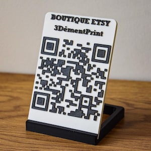 Könnte beinhalten: Ein weiß-schwarzer QR-Code-Displayständer mit dem Text "BOUTIQUE ETSY" und "3DémentPrint". Der Ständer besteht aus einem weißen, rechteckigen Stück mit einem schwarzen QR-Code und einem schwarzen Sockel.