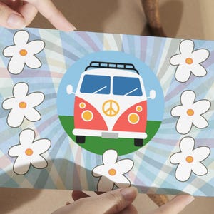Op de afbeelding: Een kleurrijke kaart met een retrobusje met een vredesteken op de voorkant, tegen een blauw-witte gestreepte achtergrond. Witte madeliefjes met oranje centra omringen het busje. De kaart heeft een oranje rand.