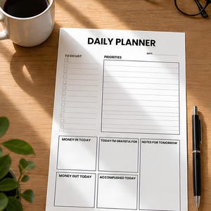 Peut inclure: Une feuille de planning quotidien blanche avec du texte noir comprenant des sections pour une liste de tâches, des priorités, la date, l'argent entrant, l'argent sortant, la gratitude, les accomplissements et des notes pour demain.