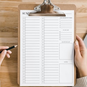 May include: A clipboard with a daily planner sheet, featuring sections for time slots, tasks, to-do list, and notes. A hand holds a pencil, ready to write. The word "SUNDAY" is at the top. A laptop is in the background.