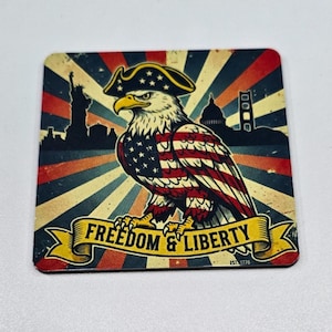 May include: Square coaster with a vintage design featuring an American bald eagle wearing a tricorn hat. The eagle's body is designed with the American flag. The background has a retro design with the text "FREEDOM & LIBERTY" and landmark silhouettes.