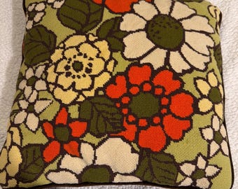 Cojín decorativo vintage de los años 70 con estampado floral bordado, reverso de terciopelo, color naranja y verde, estilo retro de mediados de siglo.