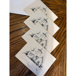 Può includere: Un set di quattro biglietti pieghevoli color bianco sporco con un disegno a tratto in inchiostro nero di un edificio con campanile. Il biglietto in basso riporta il testo The Old Sand House, Millersburg e una firma. Include buste bianche.