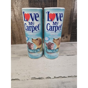 May include: Two cylindrical containers of Love My Carpet carpet and room deodorizer. The light blue packaging features a red heart, images of a dog and a cat, and the text Fights Odors, Burst of Fragrance, and Pardon My Pet. Net weight 14 oz (396g).