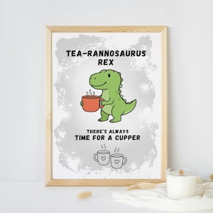 May include: A framed print featuring a green dinosaur holding a mug of tea, with the text "TEA-RANNOSAURUS REX" above and "THERE'S ALWAYS TIME FOR A CUPPER" below. Two teacups with hearts are also shown.