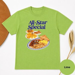 May include: Lime green t-shirt with the words "All-Star Special" in blue. The graphic depicts a breakfast plate with eggs, bacon, toast, and hash browns. A small circle at the bottom right says "Lime".