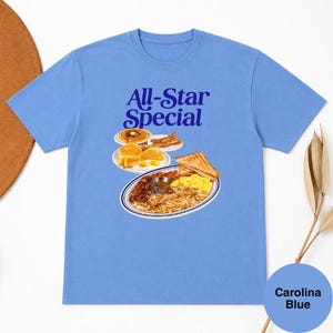 May include: Carolina blue t-shirt with the text "All-Star Special" in dark blue. The graphic features a plate of breakfast food, including pancakes, eggs, bacon, toast, and hash browns. A round Carolina Blue color swatch is in the lower right corner.