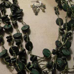 May include: A multi-strand necklace made of green jade-like beads and brown cord. The necklace is layered and has a bohemian style.