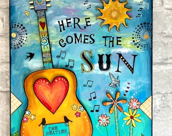 Puede incluir: Un cartel de madera pintado a mano, colorido, con una guitarra amarilla, un corazón rojo y las palabras "Here Comes The Sun" en letras negras. El cartel también presenta un sol amarillo, notas musicales y flores.