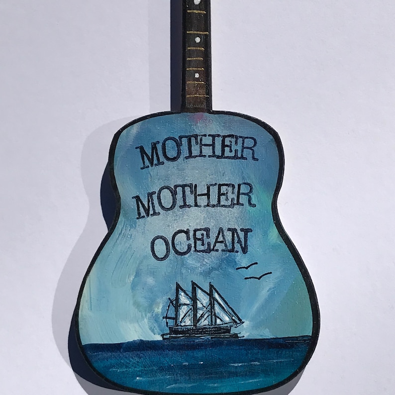 May include: A blue and white painted wooden guitar with the text "MOTHER MOTHER OCEAN" and a small sailboat on the body.