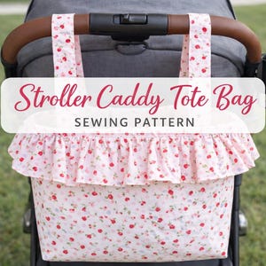 Pode incluir: Uma bolsa tote para carrinho com um padrão floral rosa e uma borda com babados. A bolsa é presa a uma alça de carrinho. O texto "Stroller Caddy Tote Bag Sewing Pattern" é exibido na bolsa.